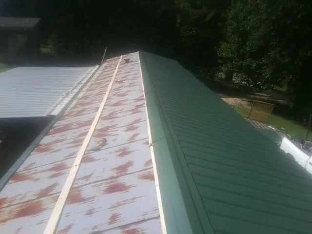 Old rusted panels beside newly installed green metal roofing — Wind Damage Roof Repair by Roofing Brothers in Rockwood