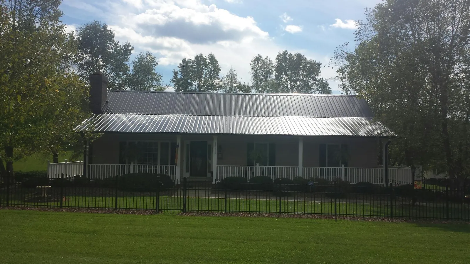 Gray metal roof on a brick ranch with a full width front porch — Gutter Guard Installation work by our crew in Rockwood