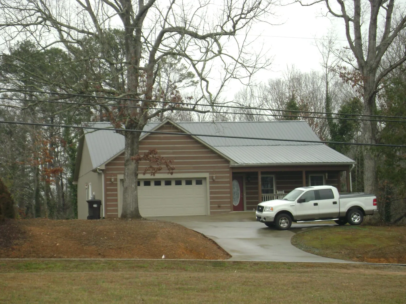 Gray metal roof on a log sided house with an attached two car garage in Rockwood