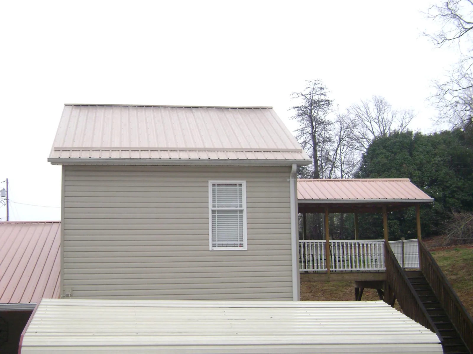 Tan metal roofs on a two story addition and attached porch, from a Roof Replacement job in Rockwood